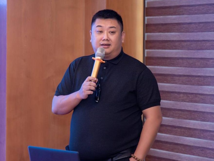Ival holding a microphone, teaching at a training session